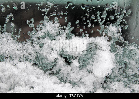 La fonte de la neige sur la vitre. giboulée sur verre. texture gris dentelle Banque D'Images