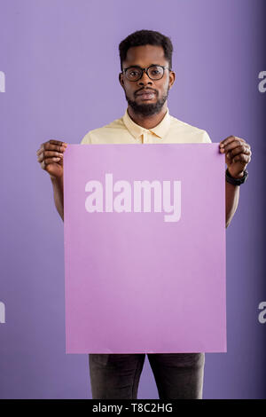 Portrait of young african american businessman confiant dans les verres montrant présentation holding blank paper plaque pour votre message texte publicitaire Banque D'Images