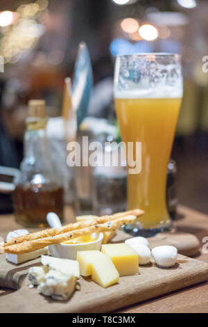 Verre de bière, l'ensemble de divers fromages avec arrière-plan flou Banque D'Images