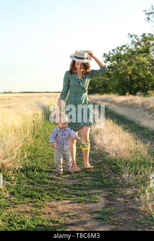 Belle femme à marcher avec son petit fils en pleine campagne sur journée d'été Banque D'Images