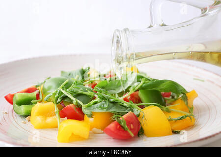 Verser de l'huile d'olive sur la salade de légumes savoureux, gros plan Banque D'Images