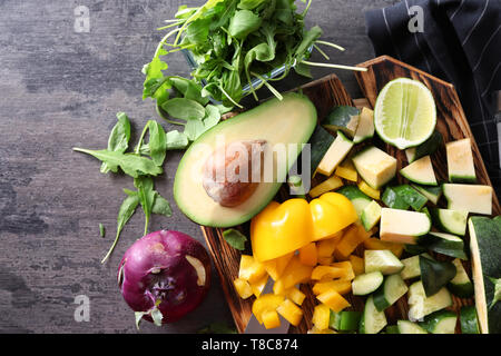 Carte avec les ingrédients pour la salade de légumes savoureux sur table gris Banque D'Images