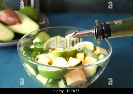 Verser de l'huile d'olive sur la salade de légumes savoureux sur la table verte, gros plan Banque D'Images