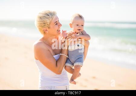 Belle mère blonde avec 4 mois bébé garçon sur la plage, Portugal Banque D'Images