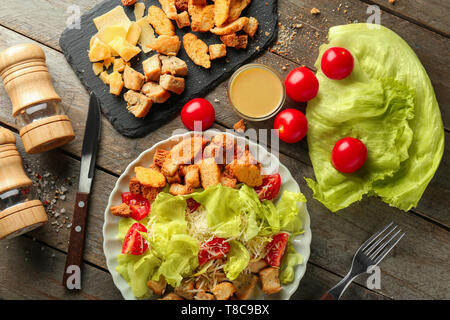 Plaque avec salade César et savoureux ingrédients sur table en bois Banque D'Images