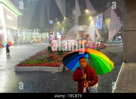 Portrait de l'homme vente de parasols sur rue pendant une douche à effet pluie à Kuala Lumpur, Malaisie Banque D'Images