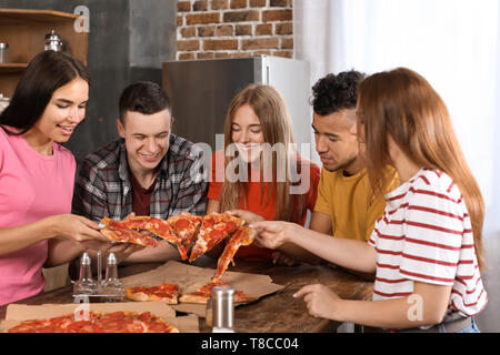 Les jeunes s'amusant à partie avec de délicieuses pizzas à l'intérieur Banque D'Images