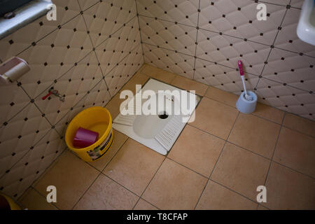 Un squat traditionnel toilettes trou dans le sol dans une station d'essence dans le nord de l'Albanie, avec pas de papier toilette et d'un seau d'eau et verseuse pour Banque D'Images