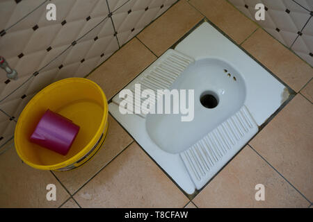 Un squat traditionnel toilettes trou dans le sol dans une station d'essence dans le nord de l'Albanie, avec pas de papier toilette et d'un seau d'eau et verseuse pour Banque D'Images