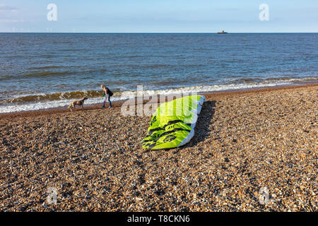 Un jeune adolescent jette son cerf-volant sur la plage à Herne Bay, prête à l'embarquement, un cerf-volant femme passant jette une balle pour son chien, Kent, UK Banque D'Images