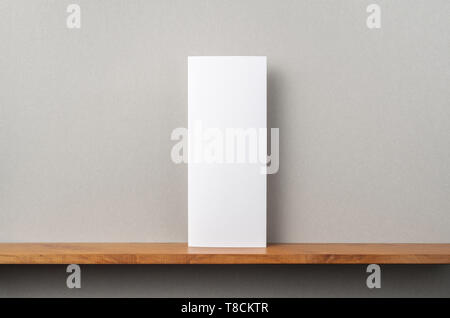 Concept design - Vue avant du support vierge brochure sur étagère et mur gris, maquette de rendu 3D pas Banque D'Images