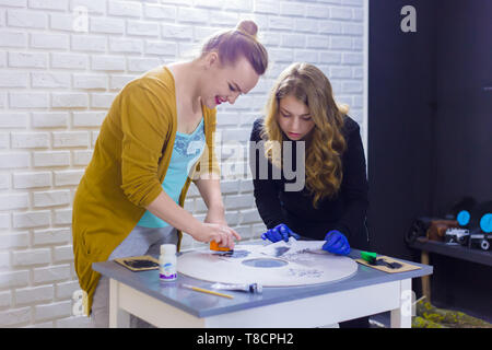 Deux femmes designers, décorateurs professionnels en bois peinture au pochoir décoration cercle à l'atelier, studio. La peinture, l'art artisanal et concept Banque D'Images