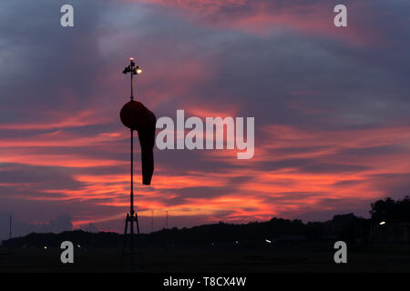 Manche à vent en vertu à l'aube sous le ciel lumineux orange rouge avec cirrus et cumulus Banque D'Images