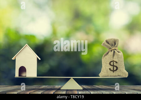 L'argent et de prêt hypothécaire,Accueil,. Le changement accueil en trésorerie concept. US Dollar dans un sac, sac modèle maison en bois mis sur les balances sur table en bois avec arbre vert bok Banque D'Images