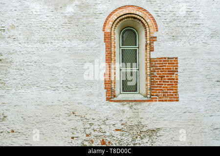 Fenêtre en arc étroit avec des bars sur la paroi de brique dans la vieille ville de Riga. Banque D'Images