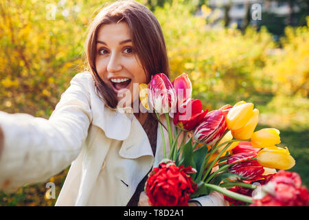 Beautiful happy woman holding bouquet de tulipes et prenant. selfies Girl having fun Banque D'Images