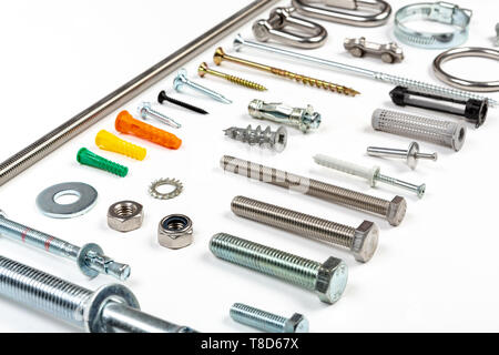 Un assortiment de charpentiers de matière, comme les vis, les boulons, les écrous de fixations, vis et clous sur un fond blanc. Banque D'Images