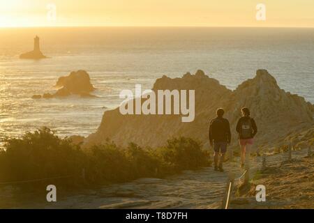 La France, Finistère, Plogoff, randonneur au coucher du soleil à la Pointe du Raz, le phare de la vieille en arrière-plan Banque D'Images