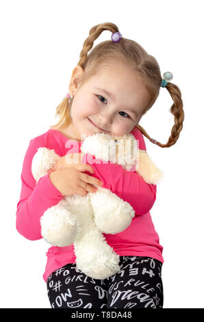 Jolie petite fille avec queues de holding peluche poupée chien isolé sur fond blanc. Adorable jeune femme souriante avec doudou. Banque D'Images