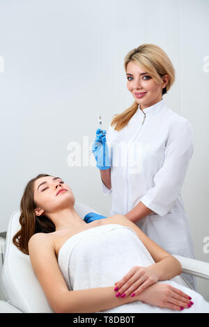 Cosmetologist doctor standing near patient et holding botulinum seringue portant des gants avant l'utilisation, des injections sous la peau. La préparation d'esthéticienne Banque D'Images