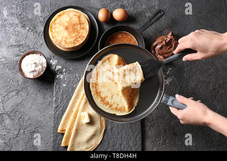 Femme tenant une poêle à frire avec du crêpe mince sur le tableau Banque D'Images