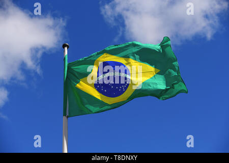 Drapeau du Brésil dans le vent en face d'un beau bleu ciel avec des nuages. Haute résolution, concept pour le voyage et le tourisme. Banque D'Images