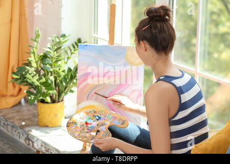 Peinture femme artiste photo, assis sur le rebord en atelier Banque D'Images