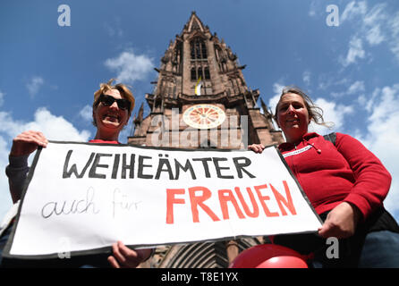 Freiburg, Allemagne. 12 mai, 2019. Deux femmes de l'initiative Maria 2.0 de la Catholic Women's Community dans l'Archevêché Freiburg tenir une bannière avec l'inscription 'Weiheämter auch für Frauen" en face de la cathédrale. Environ 400 femmes ont demandé à l'Église à repenser et à promouvoir la justice entre les sexes dans une action de protestation. Crédit : Patrick Seeger/dpa/Alamy Live News Banque D'Images