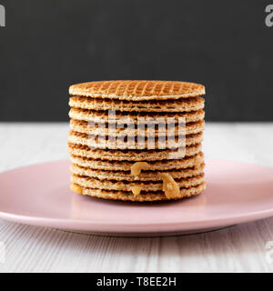 Pile de stroopwafels néerlandais fait maison avec du miel-caramel garniture sur une plaque rose, vue de côté. Close-up. Banque D'Images