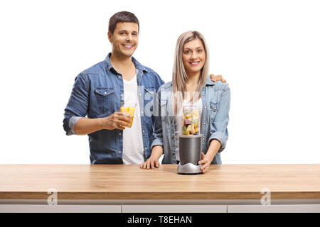 Jeune homme et femme avec des fruits dans un blender et un verre de jus smiling at the camera isolé sur fond blanc Banque D'Images