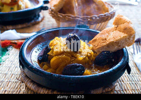 Ralentissement de la viande cuite avec les pruneaux, les amandes, les oignons et saupoudré de sésame, tajine marocain, style rustique Banque D'Images