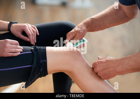 Femme athlète a blessure au genou. Close up fitness trainer permet à l'homme à genou blessé lors de l'activité sportive. Banque D'Images