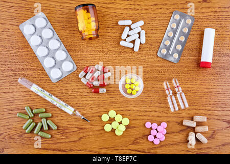Comprimés, capsules colorées, thermomètre, flacons et d'ampoules sur fond de bois. Banque D'Images