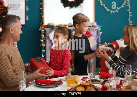 Famille heureuse donnant à chaque autre présente pendant le dîner de Noël à la maison Banque D'Images