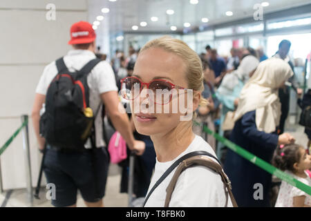 Young female traveler attendent en ligne à long contrôle de sécurité à l'aéroport de départ terminal. Dame debout dans la longue file d'attente à l'aéroport avant l'embarquement Banque D'Images