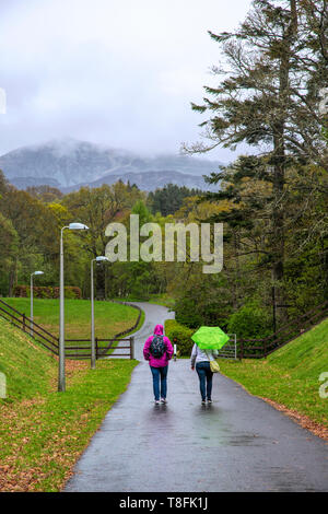 Deux personnes marchant dans un parc sous la pluie. Pitlochry, Ecosse. Banque D'Images
