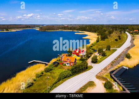 Petit village en bord de mer dans beau paysage sur une journée de printemps ensoleillée. Situé sur une étroite bande de terre à côté d'une petite route et entouré d'eau. Banque D'Images