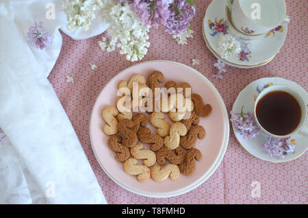 Tchèque traditionnel de la cannelle & cacao biscuits Esicka sur une plaque sur une table en bois avec un vieux-fashionned tasse de thé et de fleurs lilas. Banque D'Images