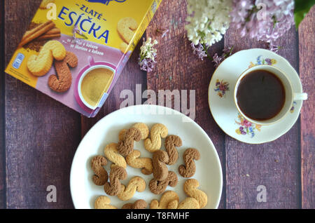 Tchèque traditionnel de la cannelle & cacao biscuits Esicka sur une plaque sur une table avec l'emballage original fort, un vieux-fashionned tasse de thé et lilas Banque D'Images