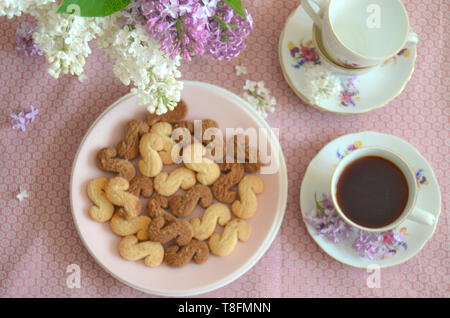 Tchèque traditionnel de la cannelle & cacao biscuits Esicka sur une plaque sur une table en bois avec un vieux-fashionned tasse de thé et de fleurs lilas. Banque D'Images