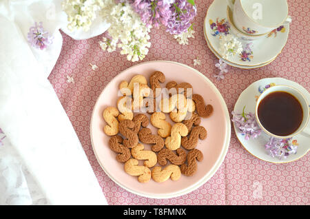 Tchèque traditionnel de la cannelle & cacao biscuits Esicka sur une plaque sur une table en bois avec un vieux-fashionned tasse de thé et de fleurs lilas. Banque D'Images