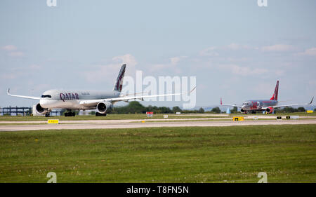 Un Qatar Airways Airbus A350 et un Boeing 737 Jet2, la préparation pour le décollage de l'aéroport de Manchester, Angleterre. Banque D'Images