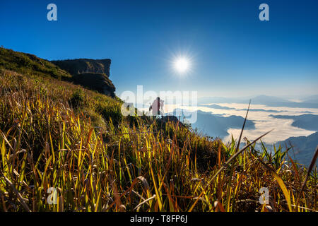 Appareil photo et photographe main tenant debout sur le rocher dans la nature. Phu chi fa montagne à Chiang Rai, Thaïlande Banque D'Images