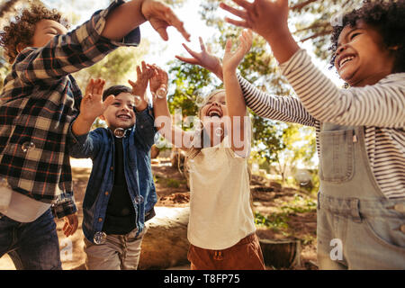 Groupe d'enfants jouant avec des bulles de savon dans la forêt. Garçon soufflant des bulles de savon avec des amis en essayant d'attraper les bulles. Banque D'Images