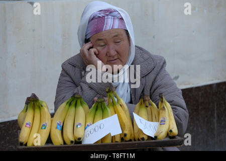 Une vieille femme ouzbek vendant des bananes dans le marché à Nukus, la capitale de la République autonome du Karakalpakstan en Ouzbékistan. Banque D'Images