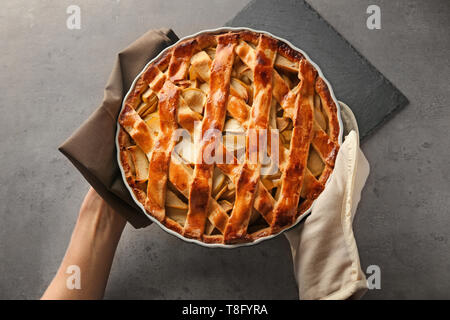 Woman putting delicious apple pie sur table Banque D'Images