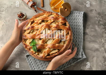 Woman putting delicious apple pie sur table Banque D'Images