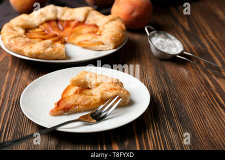 La plaque avec de délicieux morceau de galette aux pêches sur table en bois Banque D'Images