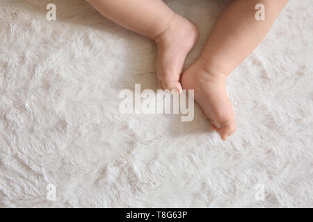 Les jambes d'adorables petits baby lying on bed Banque D'Images