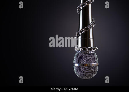 Microphone avec une chaîne, illustrant l'idée de la liberté de la presse ou la liberté d'expression sur fond sombre. Journée mondiale de la liberté de la presse concept. Banque D'Images